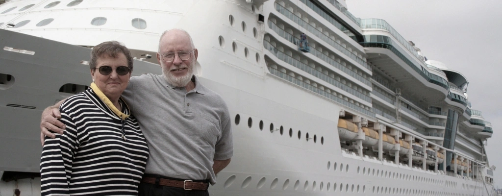 couple posing in front of a cruise ship, showcasing the convenient and reliable transfers