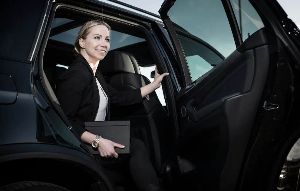 Woman stepping out of a premium airport car service vehicle