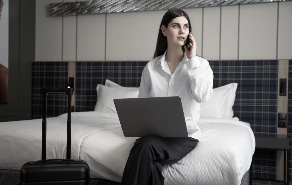 Young woman talking on her smartphone after being dropped off at her hotel for her airport transfer service